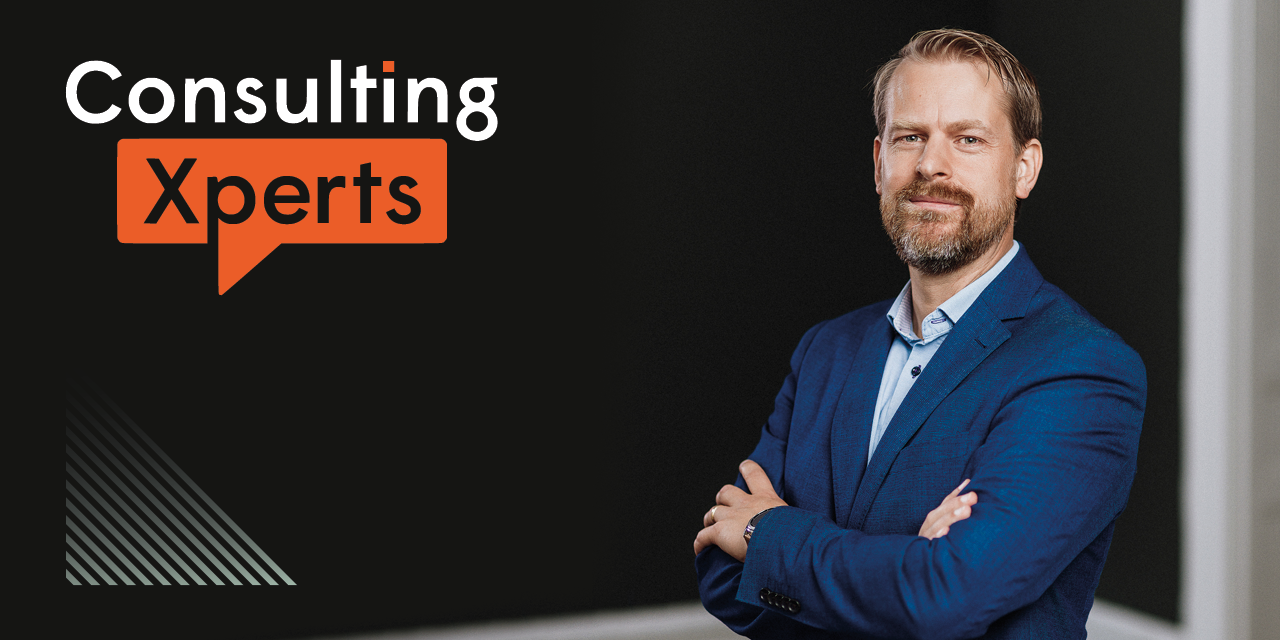 Rickard står i blå kostym. Logotypen för Consulting Xperts syns i bild.